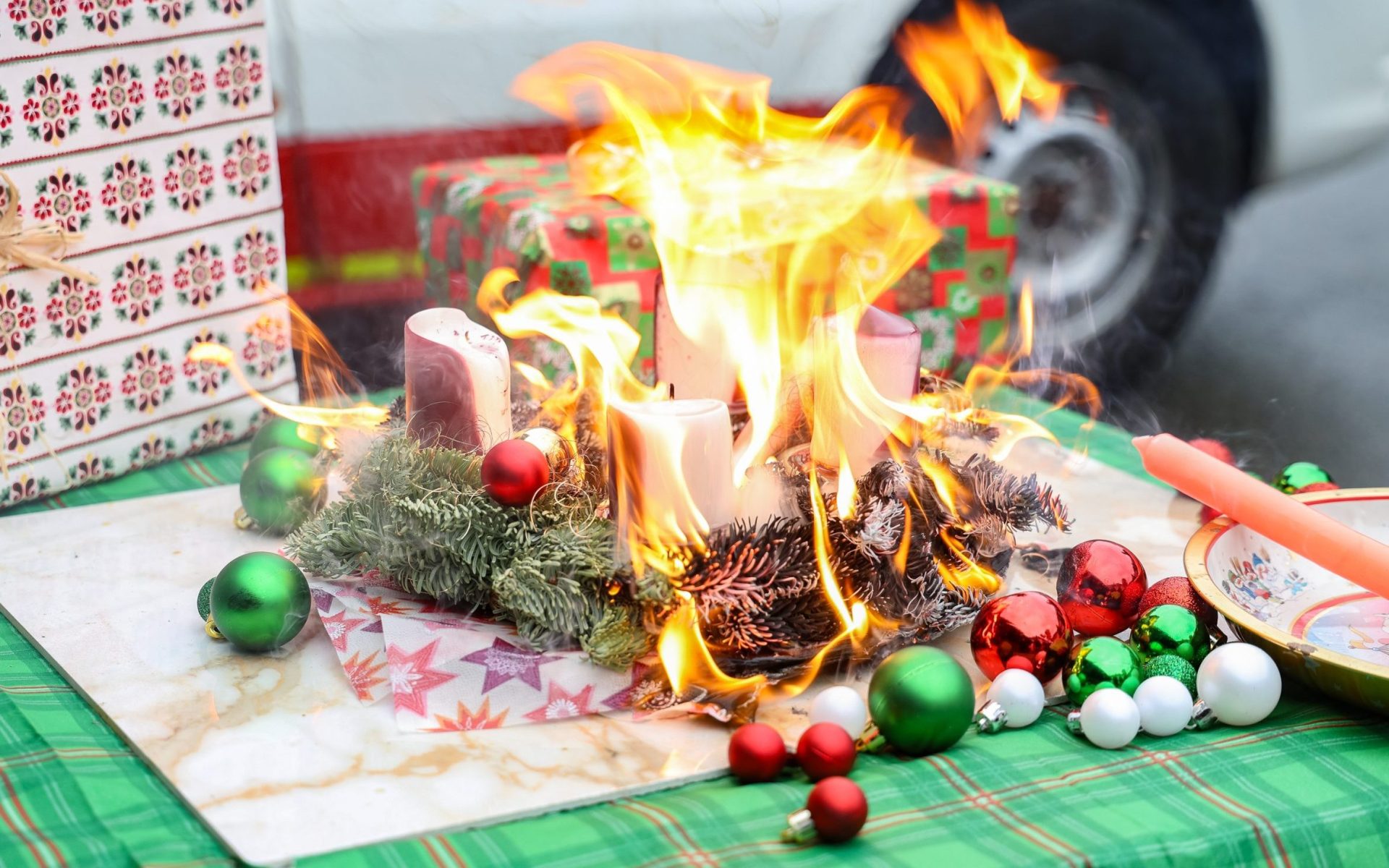 Ein brennender Adventskranz steht auf einem Tisch, die Flammen schlagen bereits nach knapp einer Minute schon über den Kranz und entzünden weitere brennbare Gegenstände.