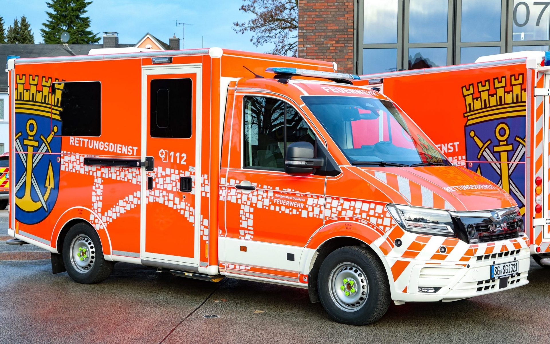 Edler Feuerwehr-Rettungswagen in leuchtendem Orange mit Blaulicht.